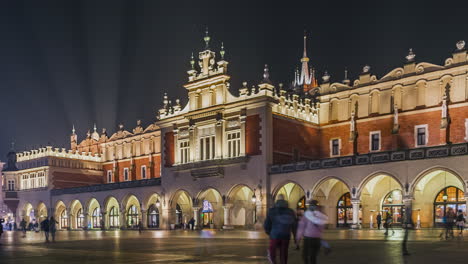 Timelapse-of-crowded-Main-Market-Square-with-Cloth-Hall-,-in-Krakow-at-night-during-Christmas-time-in-winter,-Poland---zoom-in