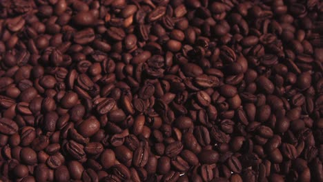 Slow-motion-overhead-footage-of-a-bed-of-coffee-beans-with-more-beans-falling-into-them-from-above