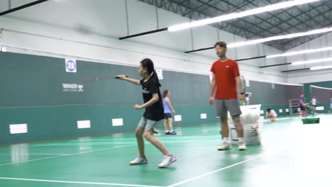 Bangkok,-Tailandia---29-De-Marzo-De-2024:-Una-Niña-Asiática-Está-Aprendiendo-Bádminton-Con-Un-Entrenador-En-El-Gimnasio.