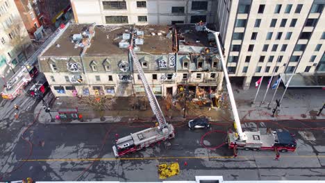 Descending-aerial-view-over-firefighters-attending-to-multiple-building-fire-in-Montreal,-Canada