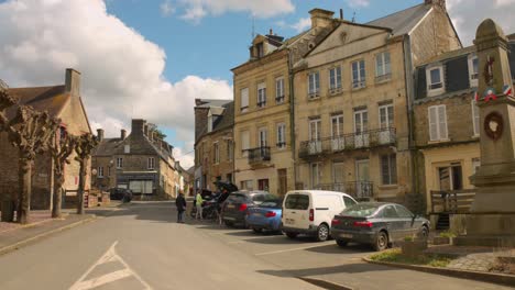 Centro-Histórico-De-Clecy-Con-Casas,-Coches-Aparcados-Y-Monumento-Conmemorativo.