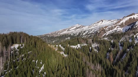 Amazing-drone,-aerial-shot-of-the-breathtaking-view-of-mountains-and-snow-capped-mountain-ranges-on-right-of-shot-in-Amden-Arvenbuel,-Switzerland-covered-by-alpine-trees-and-dotted-around-with-snow