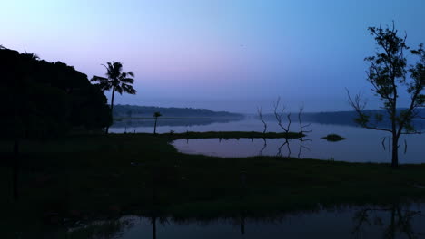 Morning-calm-lake-,-before-sun-lake-reflecting-the-atmospheric-effects-of-the-sky-and-surrounded-by-misty-fogs