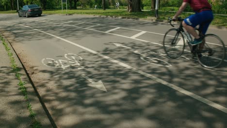 Empty-bike-lane-with-directional-arrow-and-moving-car,-urban-setting