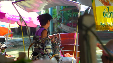 Thai-old-local-man-sailing-a-rustic-boat-in-floating-market-of-Bangkok