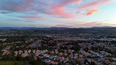 Golden-sunrise-over-Santa-Clarita,-California---rising-aerial-reveal-with-vibrant-sky