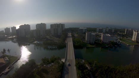 Imágenes-Aéreas-De-Drones-4k-De-Automóviles-Conduciendo-Sobre-El-Canal-Vanderbilt-En-La-Avenida-Bluebill-Que-Conduce-A-La-Playa-De-Wiggins-Pass,-Nápoles,-Florida,-Estados-Unidos