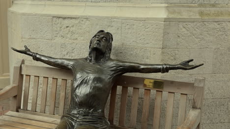 Statue-of-John-Lennon-on-a-bench,-Imagine,-Carnaby-Street,-London,-Day,-People-walk-past,-Medium-Shot