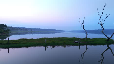 Morgens-Ruhiger-See,-Vor-Sonnenaufgang-Spiegelt-Sich-Der-See-In-Den-Atmosphärischen-Effekten-Des-Himmels-Und-Ist-Von-Nebligen-Nebeln-Umgeben