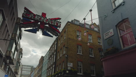 Cartel-De-Carnaby-Colgado-En-El-Aire---Union-Jack,-Carnaby-Street,-Londres,-Día,-ángulo-Bajo-Con-Edificios