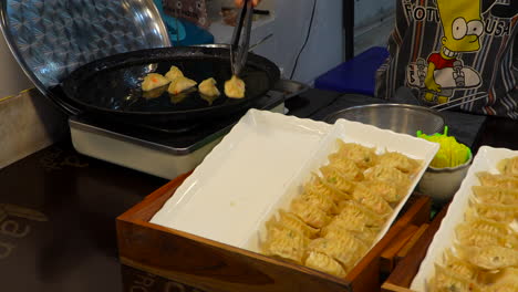 Female-chef-pan-frying-gyozas-in-food-street-market