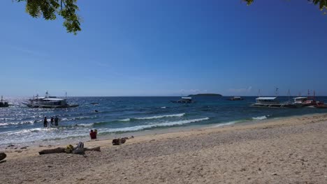 Sumérgete-En-La-Belleza-Prístina-De-Las-Playas-De-Arena-Blanca-Y-Los-Mares-Azules-De-Oslob,-Salpicados-De-Barcos-Tradicionales.