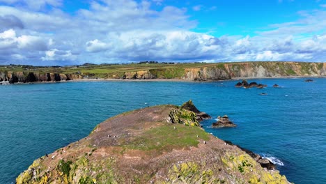 Drone-flying-over-small-island-with-nesting-seabirds-with-dark-blue-seas-and-dramatic-skies-in-Waterford-Ireland-establishing-landscape-photography