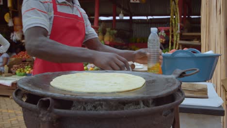 Vendedor-De-Comida-Callejera-Vertiendo-Aceite-Sobre-Pan-Plano-Chapati-En-África