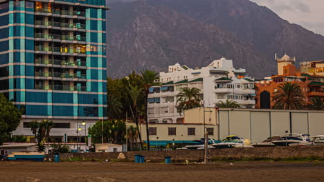 Timelapse-shot-of-tourists-and-seagulls-around-the-beach-area-with-mountains-in-the-background-in-Malaga,-Spain-at-dusk