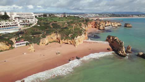 Crane-shot-revealing-Praia-Dona-Ana-beach-and-city-of-Lagos-in-the-algarve-region-of-Portugal-by-aerial-4k-drone