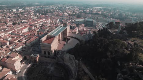 Vista-Aérea-De-Drones-De-Un-Gran-Anfiteatro-En-Una-Ciudad-Con-Una-Colina-A-La-Derecha-Durante-El-Día