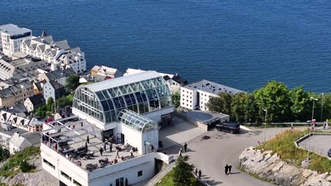 Alesund,-Norway,-Aerial-View-of-Tourists-and-Fjellstua-Viewpoint-Buildings-Above-Town-and-Bay,-Drone-Shot