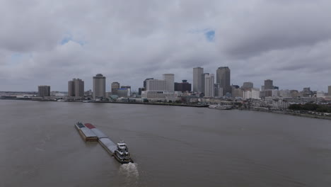 Langsames-Schwenken-Eines-Luftbildvideos-Von-Einem-Großen-Lastkahn,-Der-Den-Mississippi-Hinaufsegelt,-Mit-Der-Innenstadt-Von-New-Orleans-Im-Hintergrund