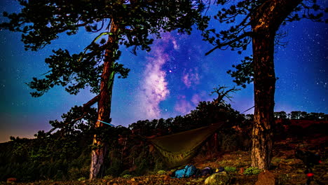 Hammock-between-trees-below-night-sky-with-moving-stars-and-galaxies