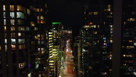 Aerial-view-flying-through-Montreal-CBD-at-night,-passing-hotels-and-office-blocks