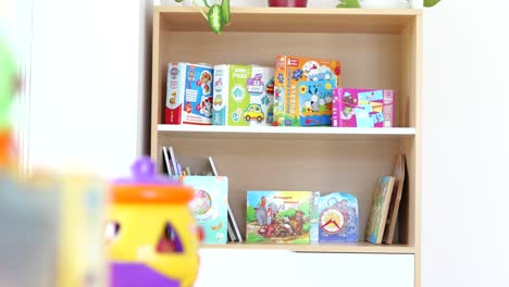 Puzzles-and-books-on-small-shelf-in-kindergarten-classroom,-slow-tracking-shot