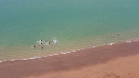 Aerial-view-over-group-of-kids-playing-and-swim-in-turquoise-colored-water,-São-Tomé-e-Principe-Island