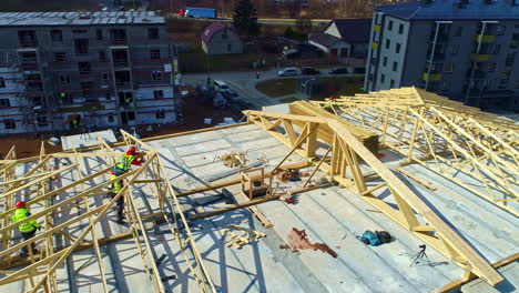 Trabajadores-Con-Ropa-Fluorescente-De-Seguridad-Construyen-Una-Estructura-De-Madera,-Escena-De-La-Ciudad-De-La-Autopista,-Toma-Aérea-De-Drones