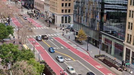 Urban-city-street-and-buildings-with-cars,-people-and-bus-lanes-visible