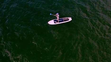 Stand-Up-Paddleboarder-Paddling-on-Wavy-Green-Lake-Water,-Aerial-Overhead