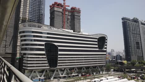 Timelapse-De-La-Sede-De-Unilever-4k-En-Un-Día-Soleado-Con-Construcción-De-Edificios-Detrás-Con-Vista-Al-Mercado-Nocturno-De-Jodd-Fairs-En-Bangkok,-Tailandia