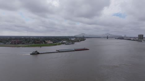 Luftaufnahmen,-Die-Sich-Um-Ein-Den-Mississippi-Hinauffahrendes-Lastkahn-Drehen-Und-Die-Innenstadt-Von-New-Orleans-Zeigen