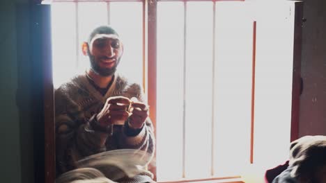 Slow-motion-shot-of-a-microcephalic-young-boy-sitting-the-the-window-of-his-home-with-the-light-coming-from-outside