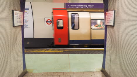 Reverse-tracking-shot-of-a-departing-of-London-Underground-train-from-within-the-tube-station,-with-commuters-onboard