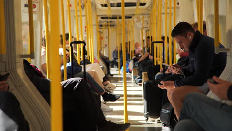 Ángulo-Estático-De-Viajeros-Sentados-A-Bordo-De-Un-Tren-De-Superficie-De-Londres-En-Movimiento,-Con-Las-Maletas-A-Cuestas,-Mientras-El-Tren-Se-Curva-Y-La-Luz-Del-Sol-Se-Desvanece