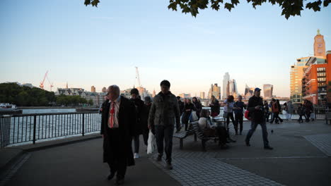 Queue-of-people-approaching-to-view-Queen-Elizabeth-II,-London-skyline-bathed-in-sunlight-along-River-Thames