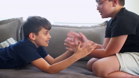 Side-view-of-two-caucasian-boys-playing-armwrestling,-having-fun-on-the-sofa-4k