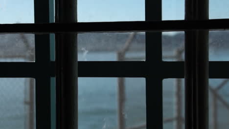 Alcatraz-Prison-Detail,-Window-With-Metal-Bars-and-High-Fence-With-Barbed-Wire