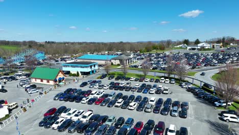 Aufsteigende-Drohnenaufnahme-Eines-Belebten-Parkplatzes-Neben-Dem-Familien-Freizeitpark-Im-Frühling