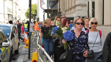 Szene-Des-Gedenkens,-Als-Menschen-Mit-Blumen-Den-Abgesperrten-Gehweg-Entlanggehen,-Nach-Der-Beerdigung-Von-Königin-Elisabeth-II.,-Im-Hintergrund-Hängt-Die-Britische-Flagge