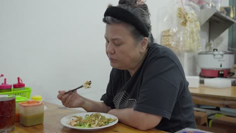 Middle-Age-Asian-Lady-eats-Char-Kway-Teow-stir-fried-rice-noodle-dish-from-China