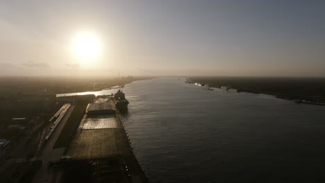 Aerial-footage-shooting-into-the-sunrise-of-the-Mississippi-River-outside-of-New-Orleans,-Louisiana