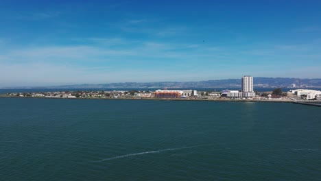 Drone-shot-of-Treasure-Island,-California-with-a-helicopter-overhead