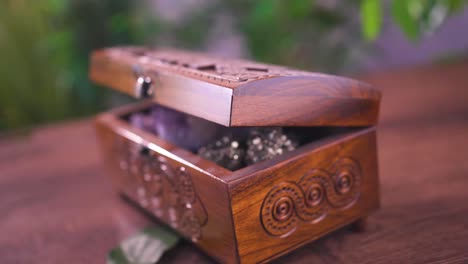 A-table-featuring-a-petite-carved-wooden-stash-box-and-an-open-book-adorned-with-a-rose-flower,-symbolizing-the-concept-of-contemplation-and-cherished-memories