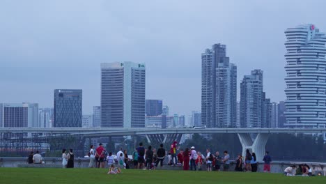 People-picnic-and-hangout-on-the-green-grass-at-Marina-barrage-rooftop-urban-park-and-water-dam-with-downtown-cityscape-on-the-skyline