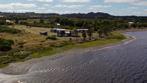 Aerial:-modern-house-on-the-coast-of-Lake-Huillinco,-in-sunnny-Chiloé,-Chile