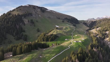 Malerische-Luftaufnahme-Des-Tals-In-Amden-Arvenbüel,-Schweiz-Mit-Straßen,-Die-Die-Berge-Hinaufführen,-Mit-Einigen-Häusern-Und-Scheunen-Am-Weg