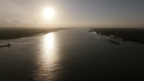 Wide-aerial-footage-flying-into-the-sun-over-the-Mississippi-River-outside-of-New-Orleans-Louisiana