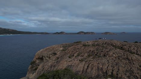 Aerial-view-of-a-hill-with-tourists-on-top-at-Cape-Le-Grand-Area-in-front-of-the-ocean