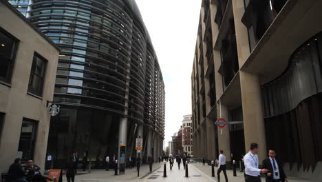 Slow-lateral-movement-in-a-pedestrian-street-within-the-finance-district-of-London-on-Walbrook-street,-with-the-underground-signage-on-the-right